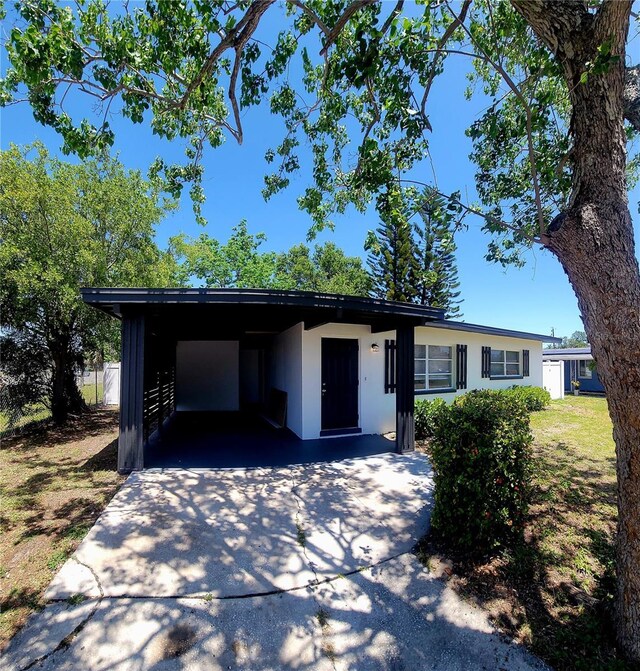 ranch-style home featuring stucco siding, driveway, and a carport
