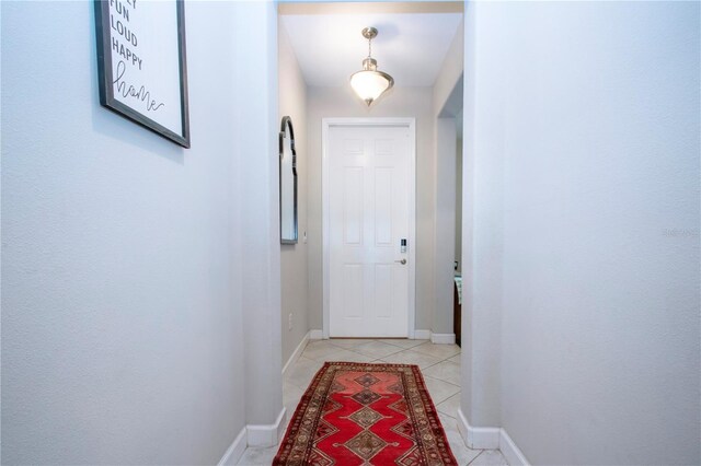 doorway to outside featuring baseboards and light tile patterned flooring