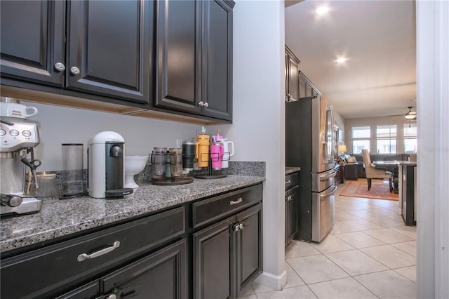 kitchen featuring freestanding refrigerator, stone countertops, open floor plan, a ceiling fan, and light tile patterned floors
