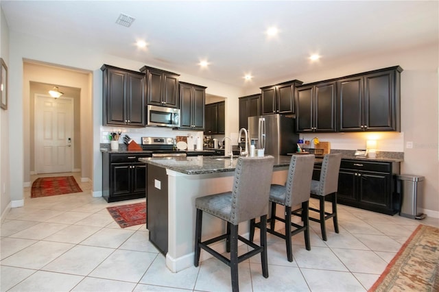 kitchen featuring light tile patterned floors, stainless steel appliances, a kitchen bar, and visible vents