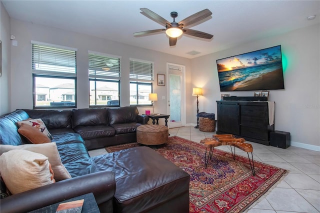 tiled living room featuring a ceiling fan, baseboards, and plenty of natural light