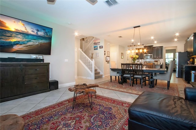living room with visible vents, an inviting chandelier, baseboards, stairway, and light tile patterned floors