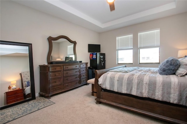 bedroom featuring a ceiling fan, a raised ceiling, and light carpet