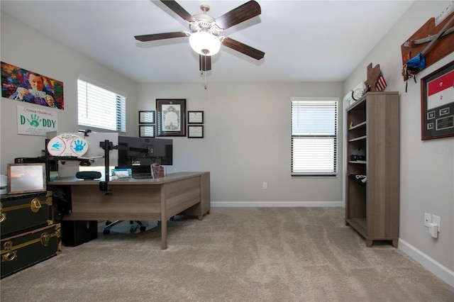 carpeted office space with a ceiling fan and baseboards