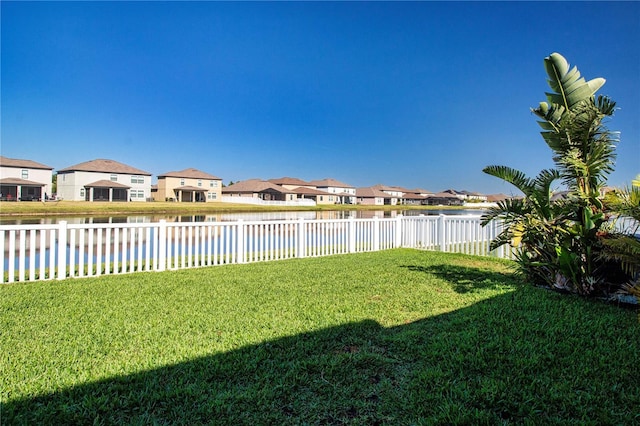view of yard with a water view, a fenced backyard, and a residential view