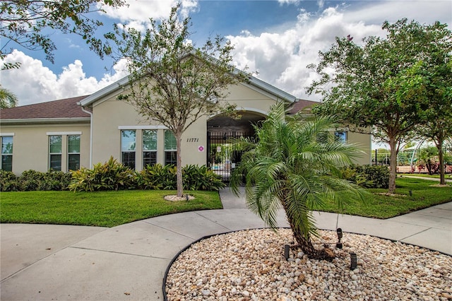 view of front of home with stucco siding, a front yard, and fence