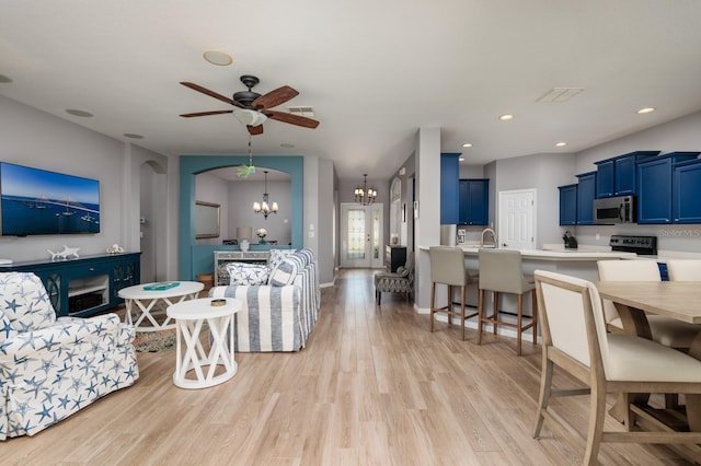 living room featuring recessed lighting, light wood-style flooring, ceiling fan with notable chandelier, and visible vents