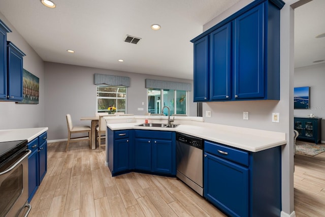 kitchen featuring appliances with stainless steel finishes, a sink, light wood-type flooring, visible vents, and blue cabinets