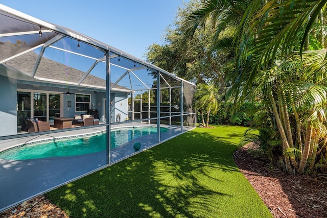 pool with ceiling fan, outdoor lounge area, a patio area, glass enclosure, and a yard