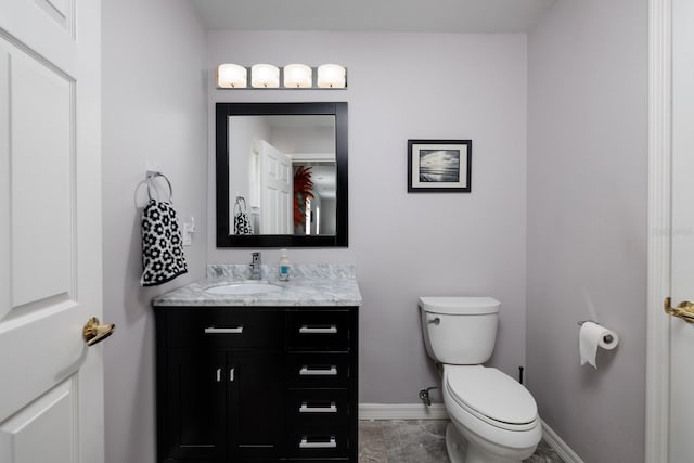 half bathroom with toilet, baseboards, and vanity