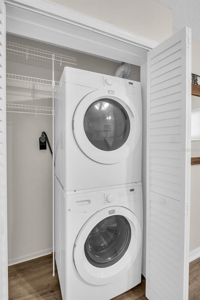 4725 Cove Cir Unit 601, Saint Petersburg, FL 33708 - clothes washing area featuring stacked washing machine and dryer, wood finished floors, and baseboards