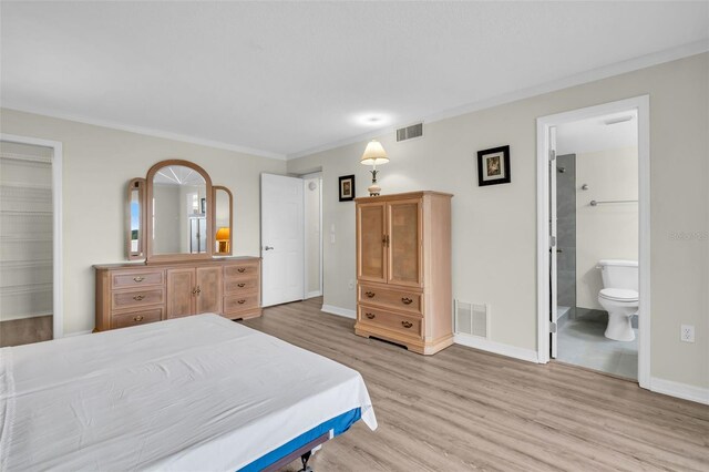 4725 Cove Cir Unit 601, Saint Petersburg, FL 33708 - bedroom featuring light wood-style flooring, baseboards, a spacious closet, ensuite bathroom, and ornamental molding