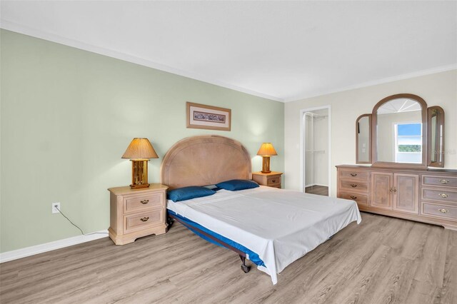 4725 Cove Cir Unit 601, Saint Petersburg, FL 33708 - bedroom with light wood finished floors, a spacious closet, crown molding, a closet, and baseboards