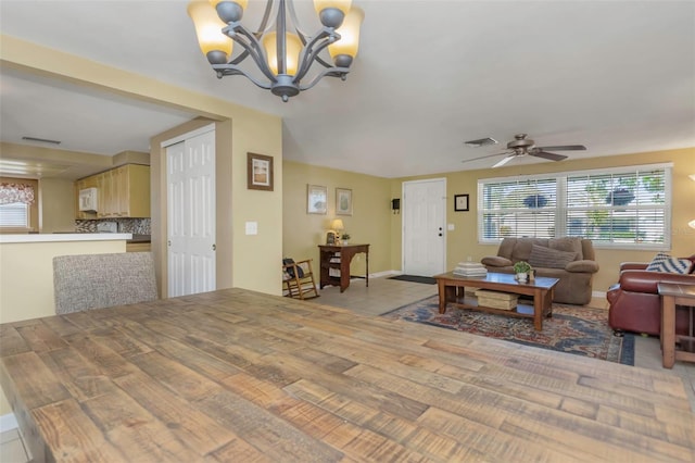 living room featuring visible vents, baseboards, and ceiling fan with notable chandelier