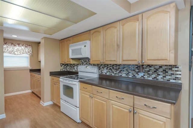 kitchen featuring dark countertops, light brown cabinets, white appliances, light wood-style flooring, and baseboards