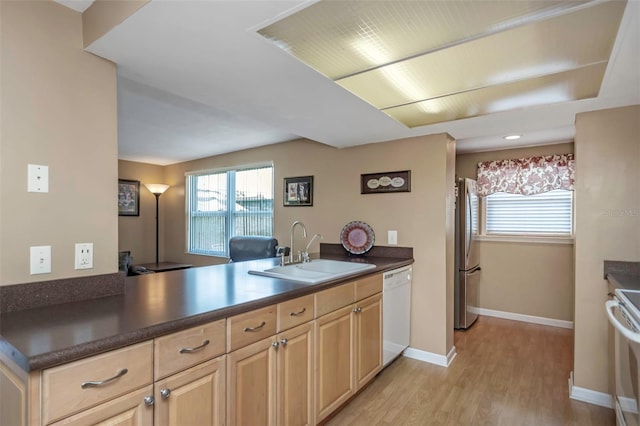 kitchen featuring electric range, white dishwasher, light brown cabinetry, a sink, and freestanding refrigerator