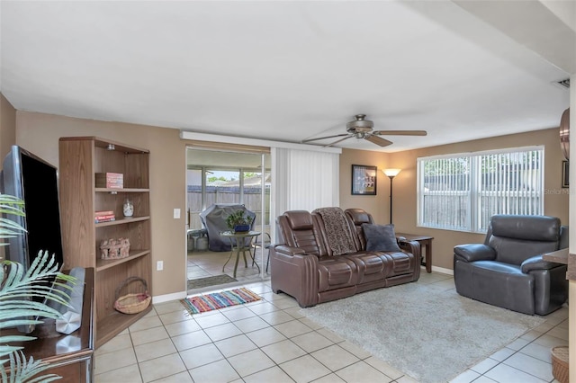 living area featuring plenty of natural light, a ceiling fan, baseboards, and light tile patterned floors