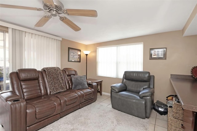 tiled living area featuring plenty of natural light, a ceiling fan, and baseboards