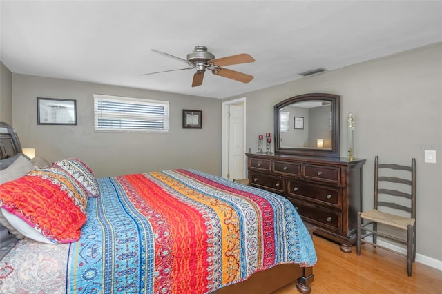 bedroom featuring visible vents, a ceiling fan, baseboards, and wood finished floors
