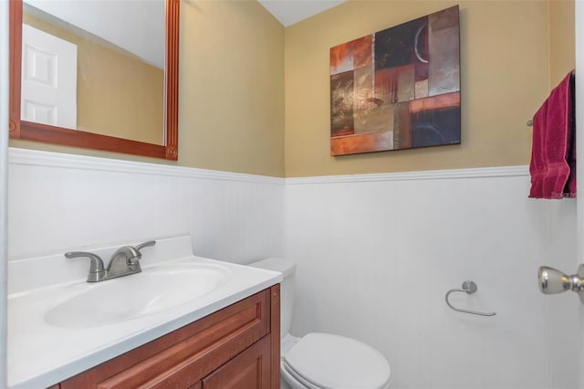 bathroom featuring vanity, wainscoting, and toilet