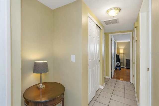 corridor with light tile patterned floors, baseboards, and visible vents