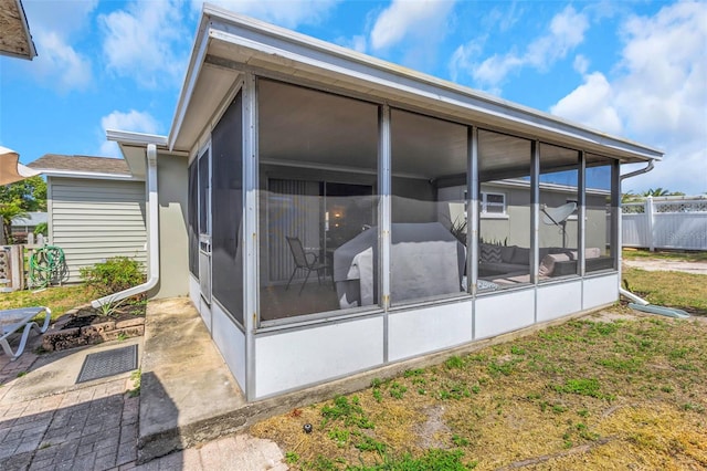 back of property with fence and a sunroom