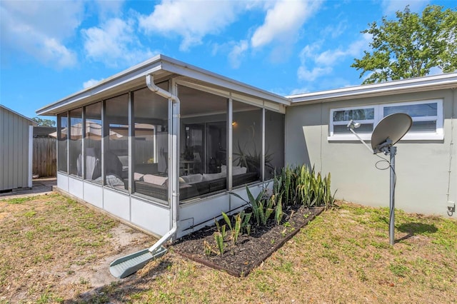 back of property featuring a lawn, a sunroom, and stucco siding
