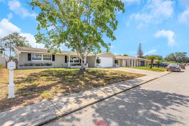 single story home with an attached garage, a front lawn, stucco siding, and driveway