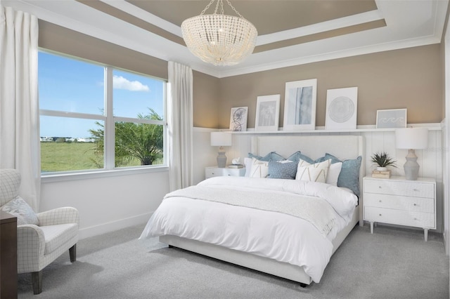 bedroom with a tray ceiling, a notable chandelier, and carpet