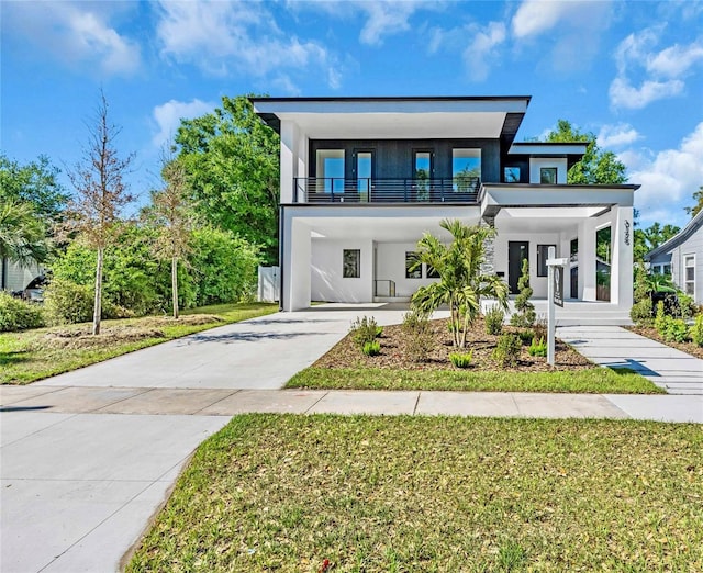 view of front of house featuring a carport, stucco siding, concrete driveway, and a front yard