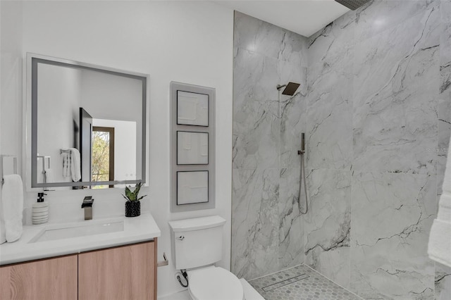 bathroom with toilet, a marble finish shower, and vanity