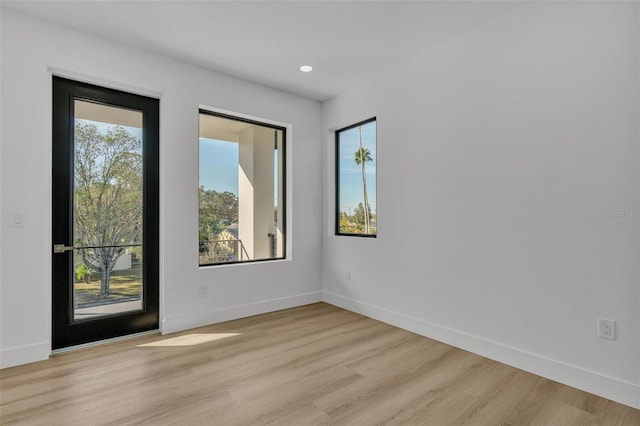 spare room with recessed lighting, baseboards, a healthy amount of sunlight, and light wood-type flooring