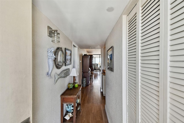 hallway featuring a textured wall and dark wood-style floors