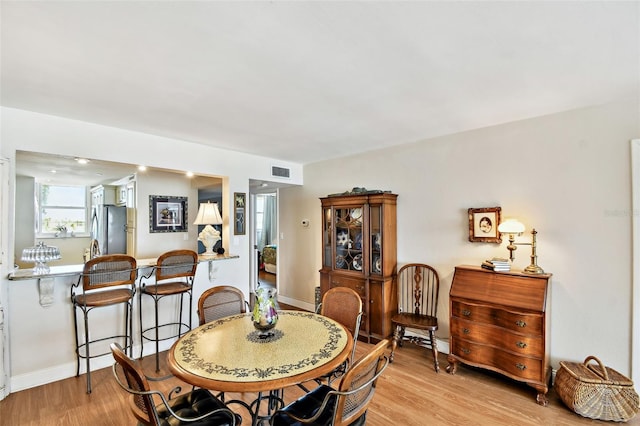 dining room featuring a baseboard radiator, light wood-style flooring, baseboards, and visible vents