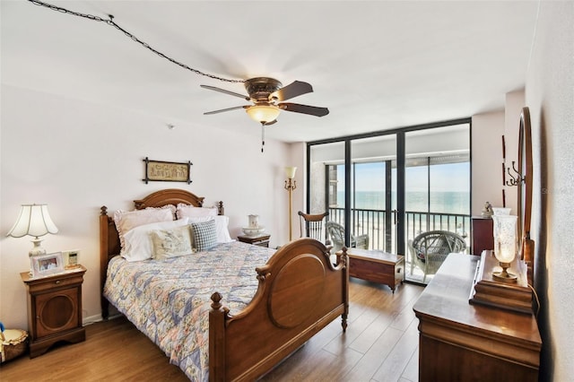 bedroom featuring a water view, wood finished floors, access to exterior, and ceiling fan