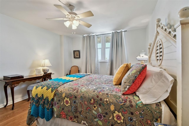 bedroom featuring baseboards, wood finished floors, and a ceiling fan