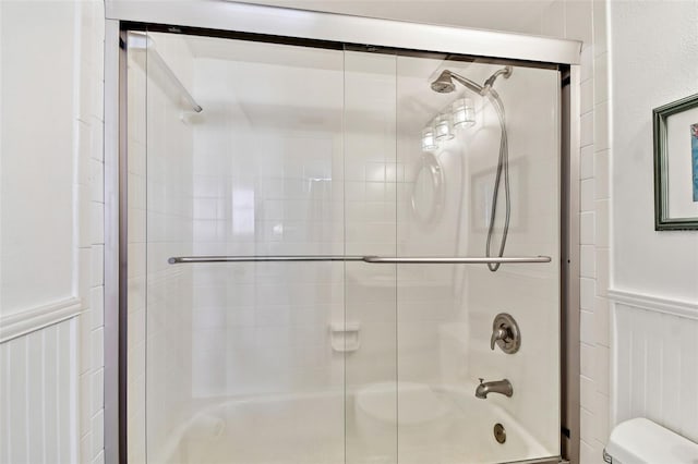 full bathroom featuring toilet and combined bath / shower with glass door