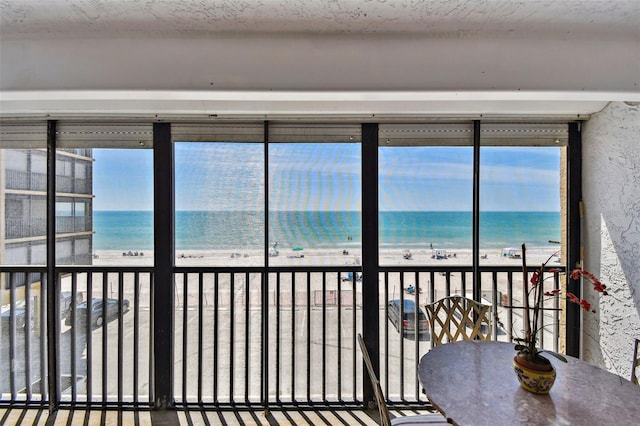 sunroom / solarium with a water view and a beach view