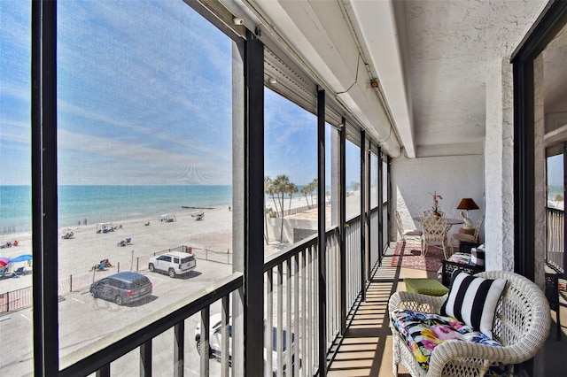 sunroom / solarium featuring a water view and a beach view