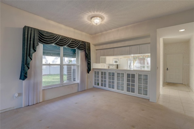 6330 99th Way N Unit 14F, Saint Petersburg, FL 33708 - spare room featuring light colored carpet, a textured ceiling, and light tile patterned floors