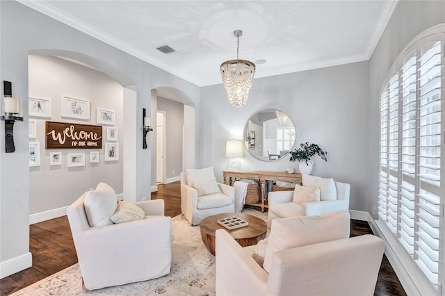 living room featuring visible vents, arched walkways, wood finished floors, an inviting chandelier, and ornamental molding