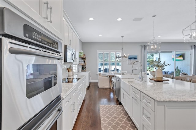 kitchen featuring recessed lighting, white cabinets, a sink, appliances with stainless steel finishes, and a notable chandelier