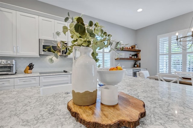 kitchen featuring a healthy amount of sunlight, decorative backsplash, white cabinets, and black electric stovetop