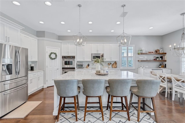 kitchen featuring visible vents, a kitchen island, white cabinets, a chandelier, and appliances with stainless steel finishes
