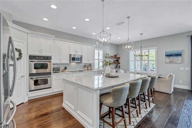 kitchen with a notable chandelier, appliances with stainless steel finishes, a sink, white cabinetry, and dark wood-type flooring
