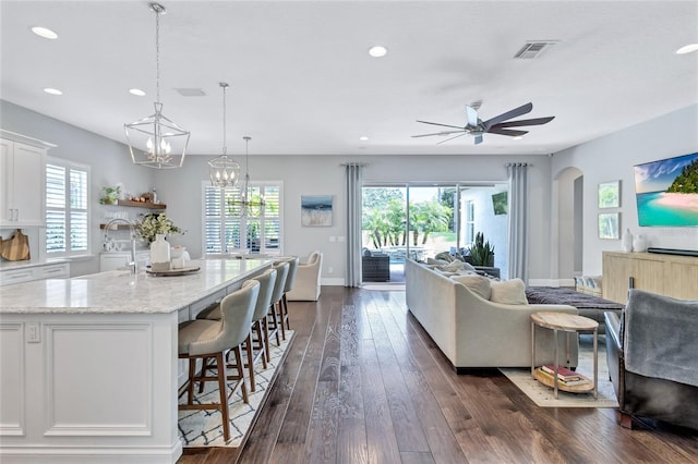 living area with recessed lighting, dark wood-style floors, plenty of natural light, and ceiling fan with notable chandelier