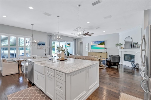 kitchen featuring visible vents, a glass covered fireplace, a sink, dark wood finished floors, and appliances with stainless steel finishes