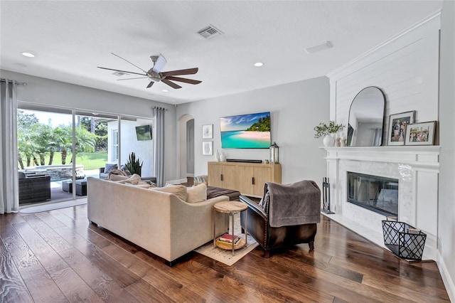 living room with ceiling fan, recessed lighting, a high end fireplace, arched walkways, and dark wood finished floors