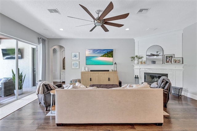 living area with visible vents, a ceiling fan, and arched walkways