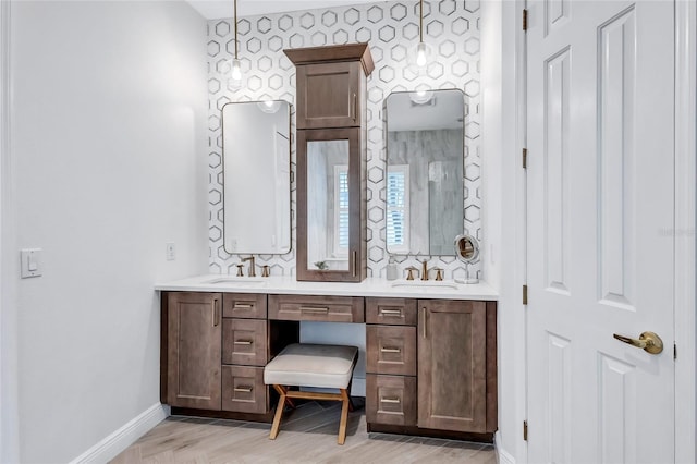 full bathroom with baseboards, a sink, wood finished floors, and double vanity